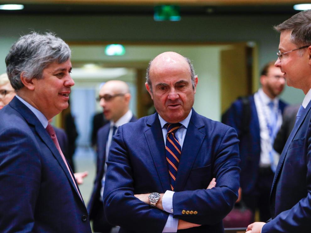 De Guindos, junto al presidente del Eurogrupo, Mario Centeno, y el vicepresidente de la Comisión Europea, Valdis Dombrovskis.
