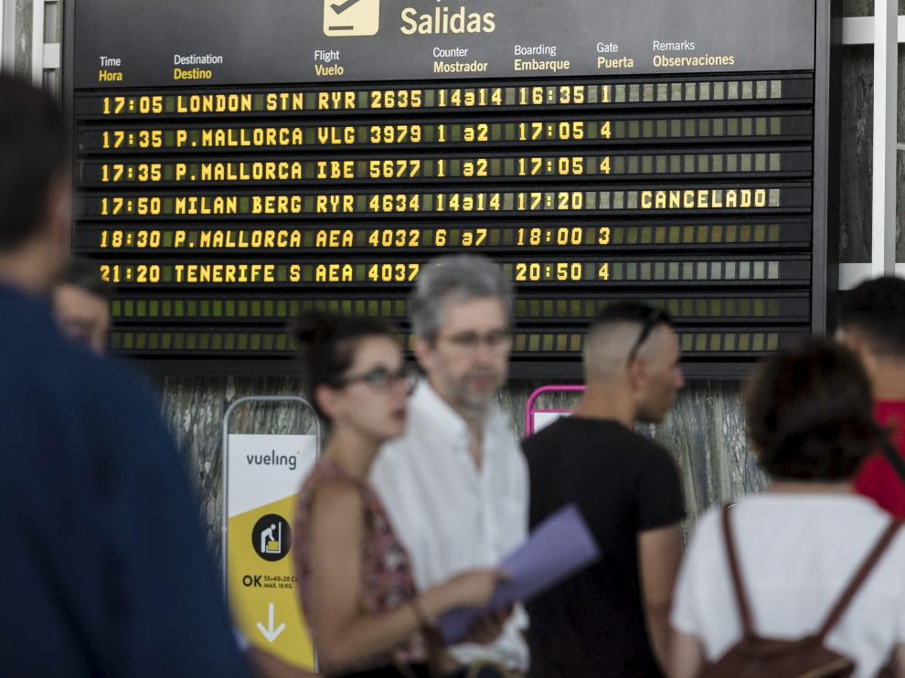 Un grupo de afectados, ayer ante el panel que anuncia la cancelación del vuelo a Bérgamo.