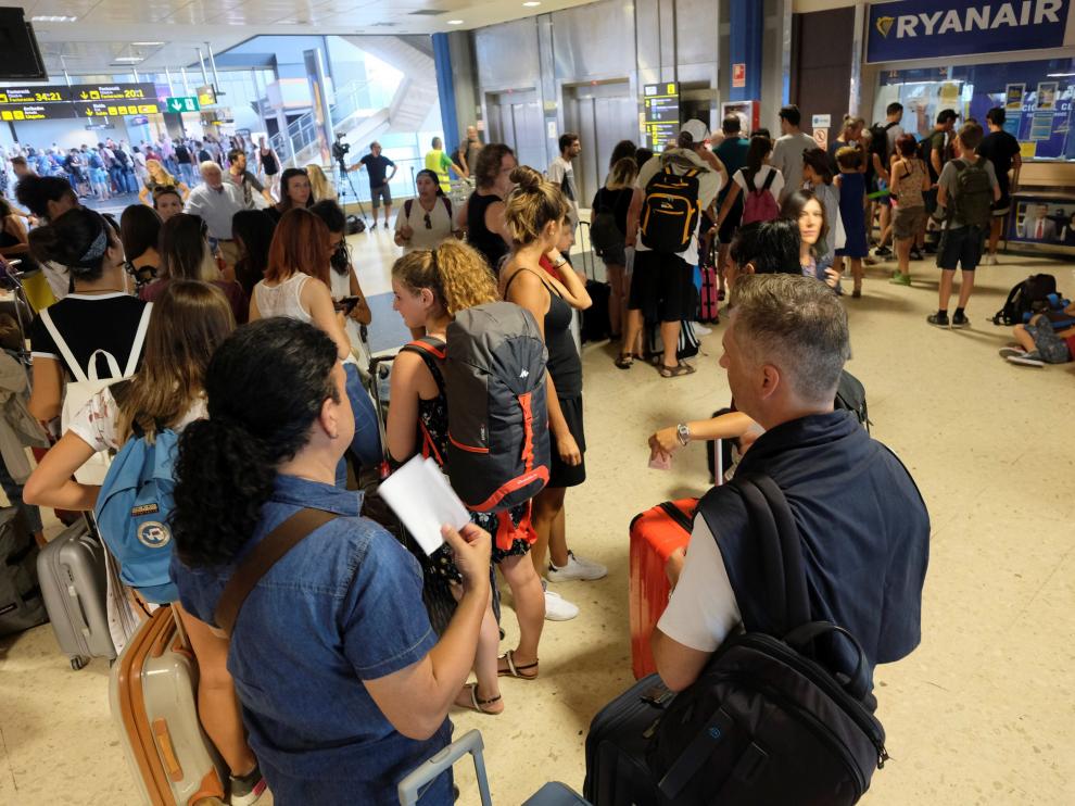Pasajeros de Ryanair afectados por la huelga hacen cola en el mostrador de información del aeropuerto de Valencia.