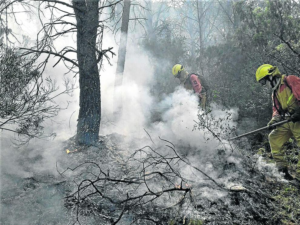 Miembros del operativo de extinción de incendios apagan un fuego causado por un rayo en Zuera