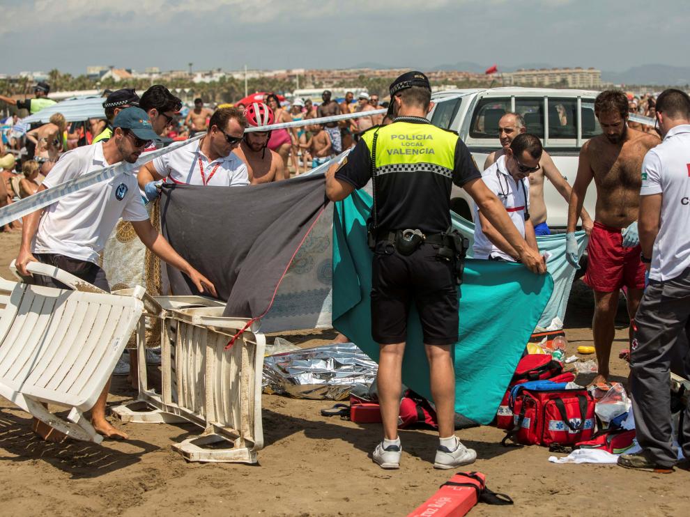 Miembros de la Cruz Roja, junto al cuerpo de un hombre que se ha ahogada en aguas de la playa de la Malvarrosa, en Valencia.