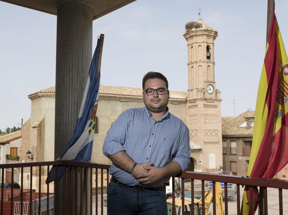 El alcalde, en el ayuntamiento de Pinseque, con la iglesia de San Pedro Mártir al fondo.