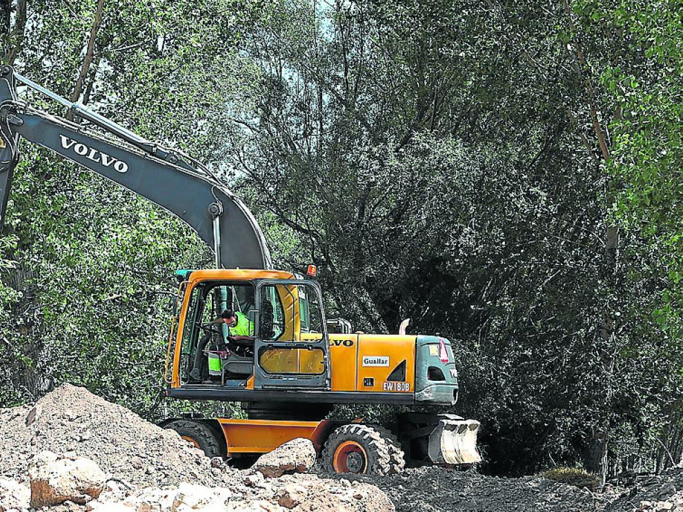 La excavadora retira los depósitos para abrir paso al río.