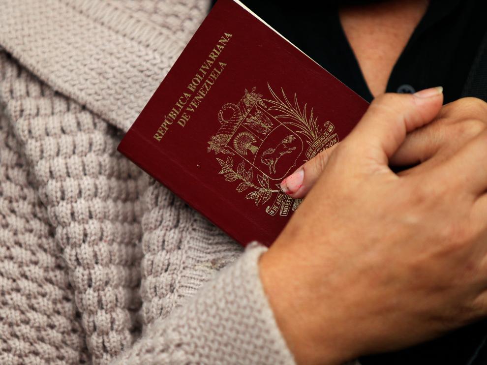 Una mujer venezolana sostiene su pasaporte a la espera de cruzar el paso fronterizo entre Ecuador y Perú.