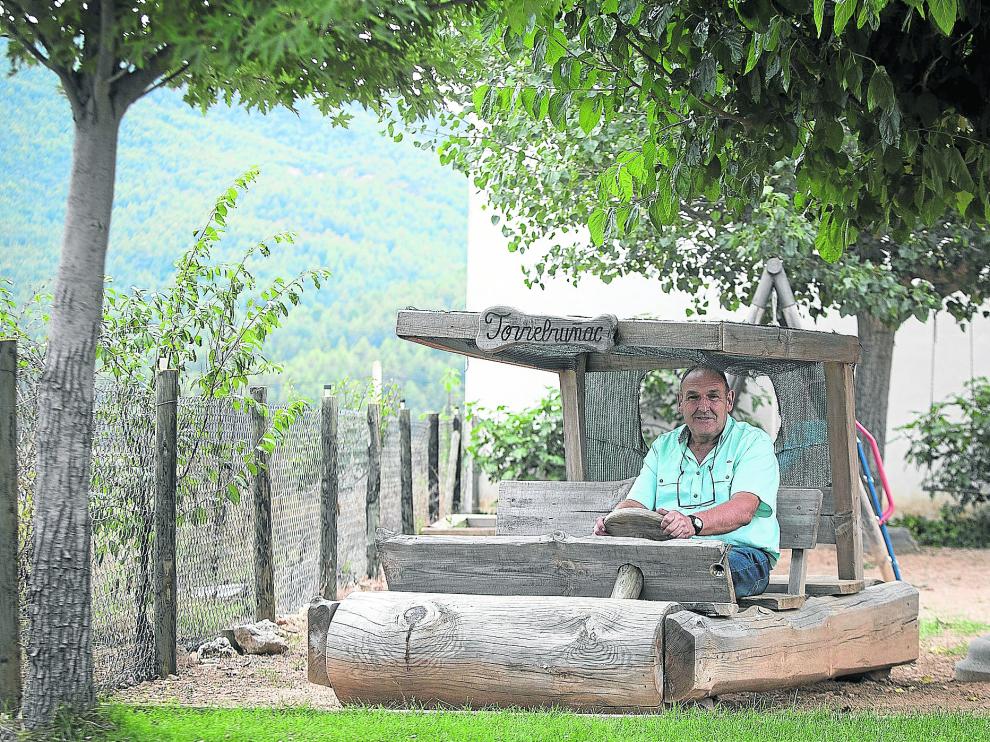 El fundador de Torrebruñac, José Román, en el troncomóvil a tamaño 'natural' que tiene en el jardín y que ha tallado él mismo.
