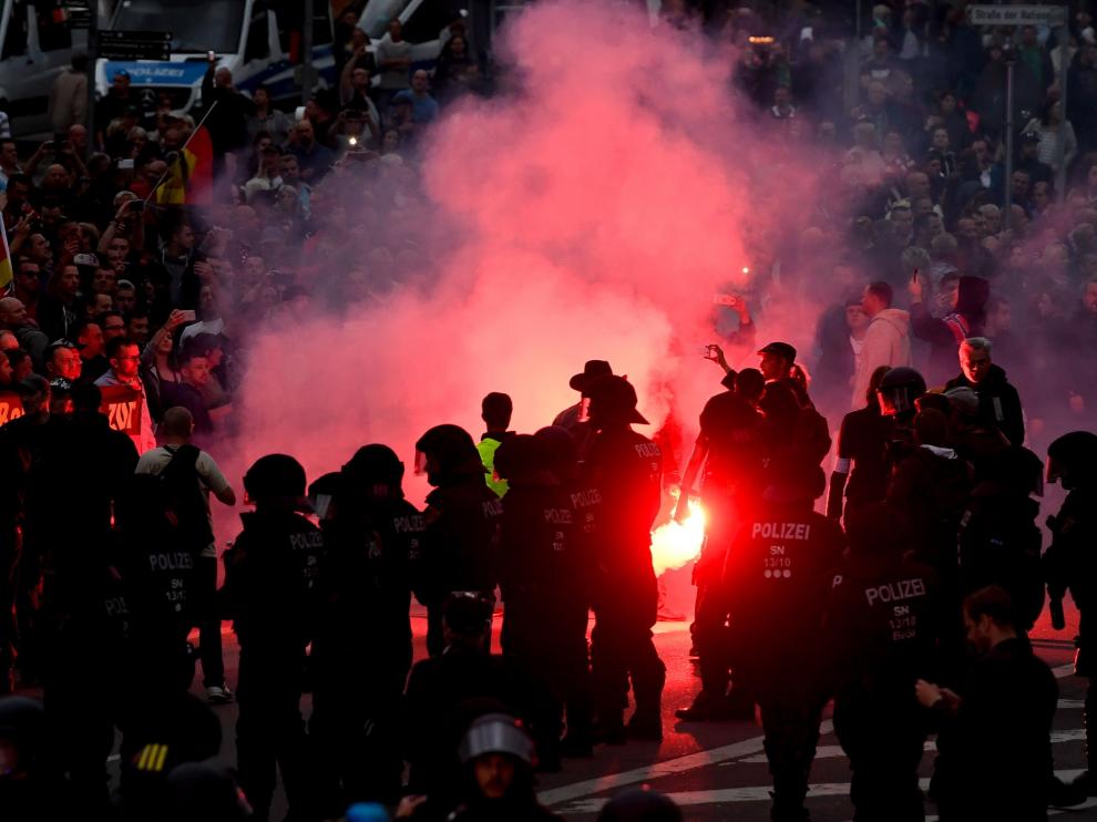 Manifestantes de derecha prenden bengalas mientras enfrentan a la policía antidisturbios en Chemnitz (Alemania).