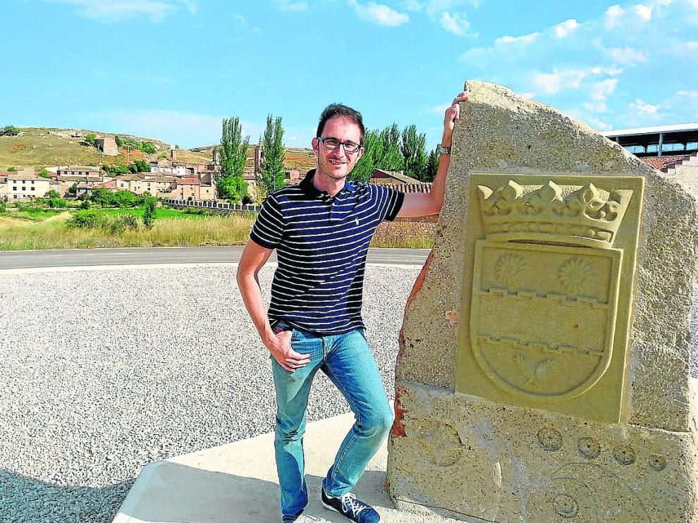 El alcalde, en la rotonda de entrada a Villarroya del Campo, con el escudo del pueblo.