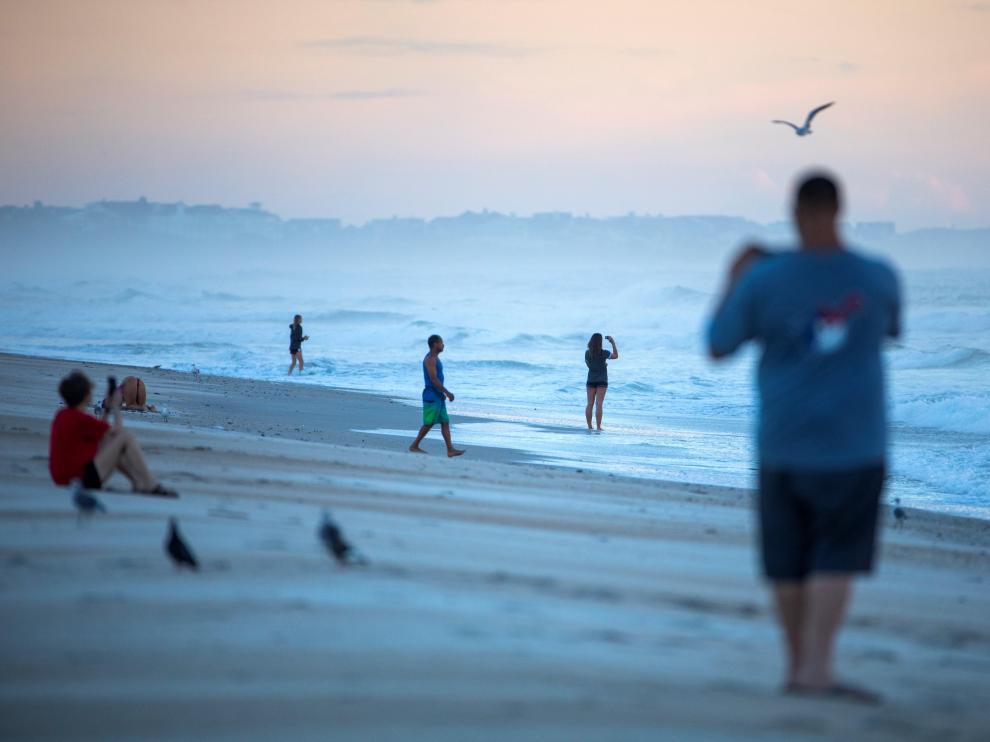 Varias personas toman fotografías al amanecer en una playa de Carolina del Norte.