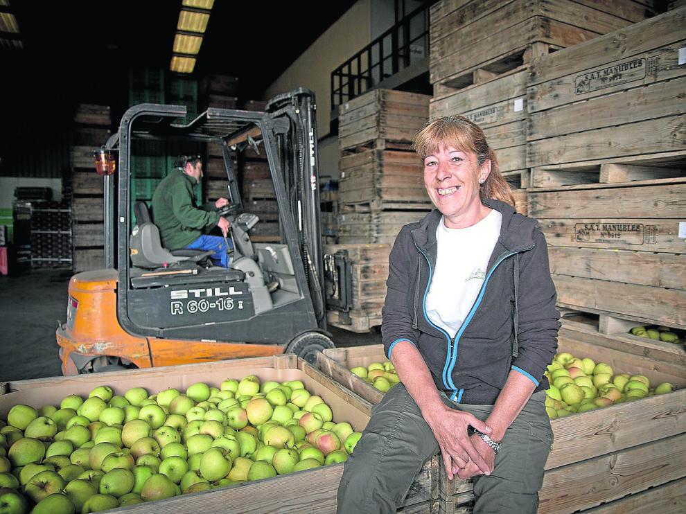 La agricultora Fina Martínez sonríe junto a las manzanas recolectadas