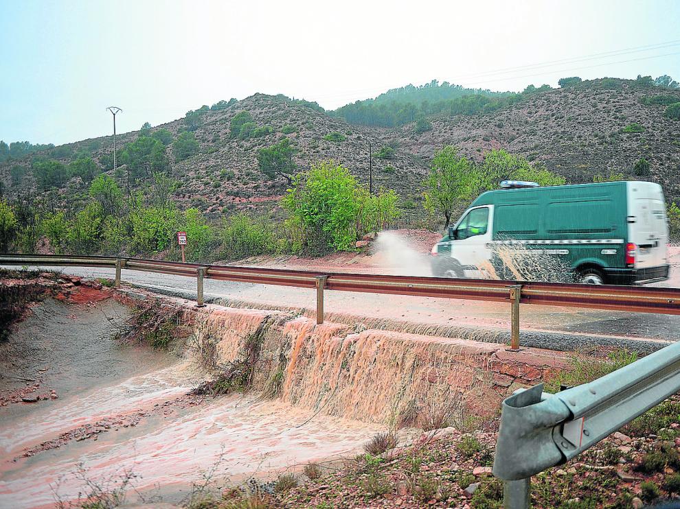 Una torrentera anega y cruza la carretera N-330, también cortada por la caída de rocas, entre Teruel y Villastar.