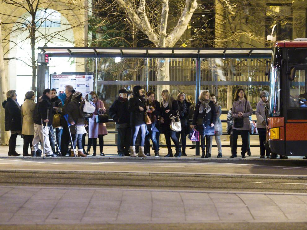 Usuarios del bus urbano esperando bajo una marquesina en la plaza de Aragón.