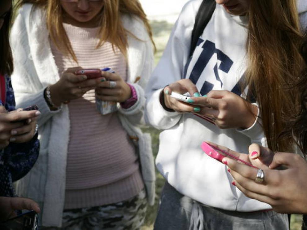 Varios jóvenes usando móviles.