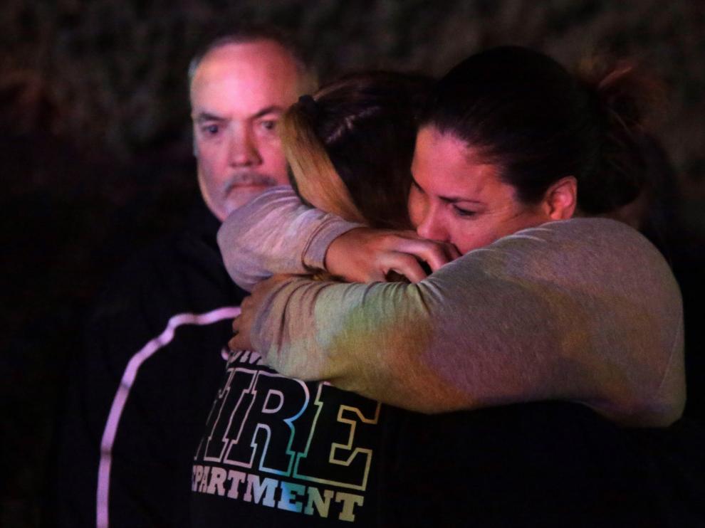 Una mujer que huyó del lugar del tiroteo en un bar de California abraza a sus familiares.