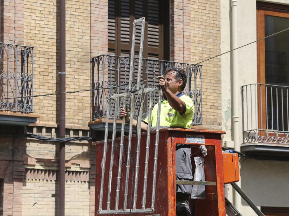 Un operario de las brigadas municipales coloca la iluminación de las Fiestas de San Lorenzo