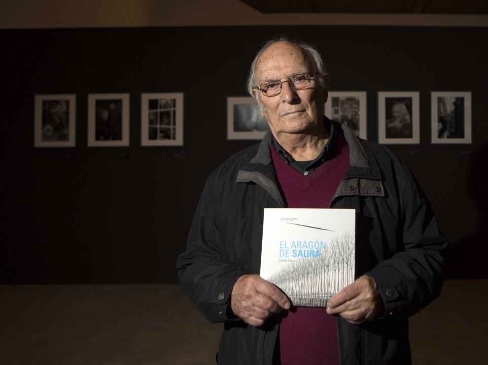 Carlos Saura con el libro de fotografías y paisajes pintados de Aragón.