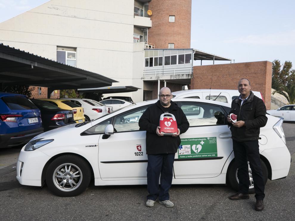 Javier Burgos, a la izquierda, y Ángel Hernández, muestran el desfibrilador instalado en el taxi 'cardioprotegido'.