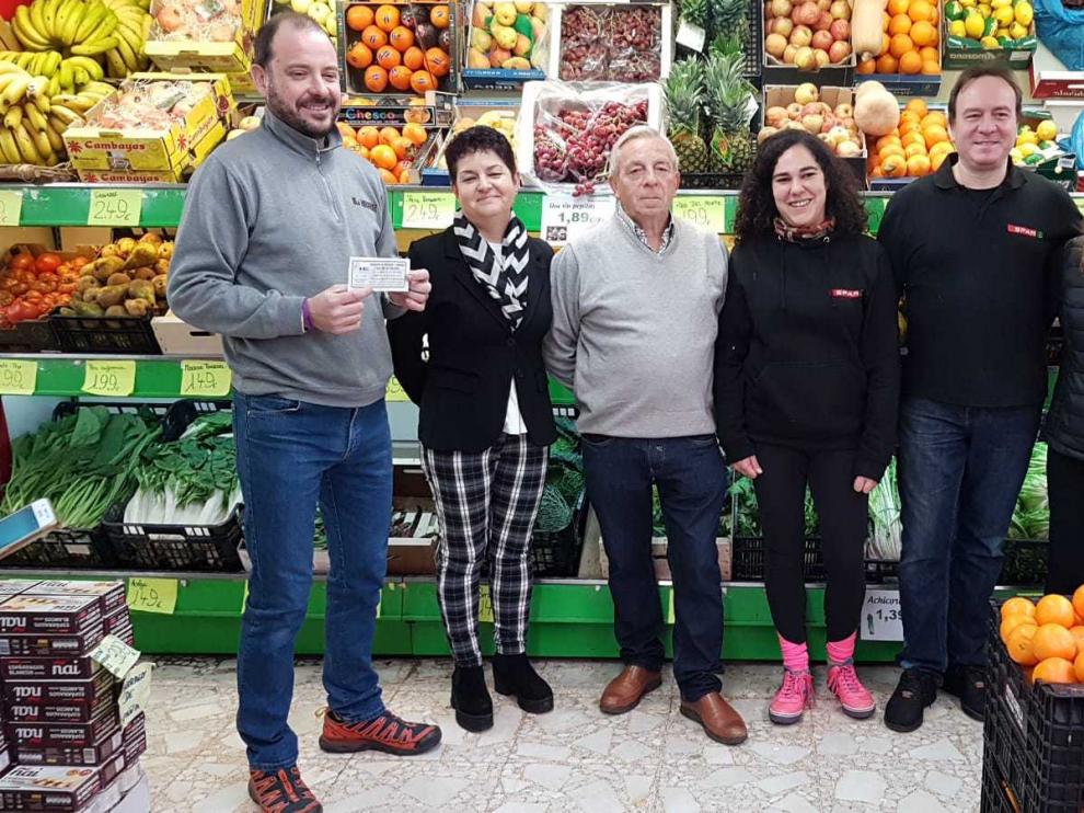 Óscar Aguado, primero por la izquierda, con el boleto ganador de los 6.000 euros en compras de la ACT en la tienda de alimentación que ha repartido el premio.