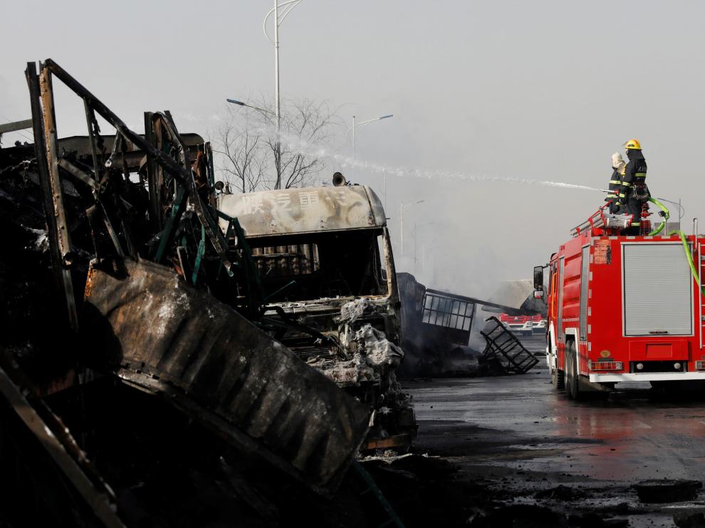 Bomberos apagando el fuego de uno de los camiones incendiados.