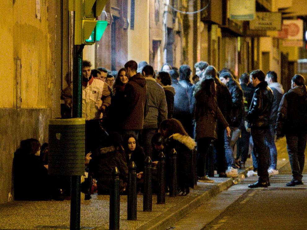 Un grupo de jóvenes consume alcohol a las puertas de un bar en la zona del Rollo.