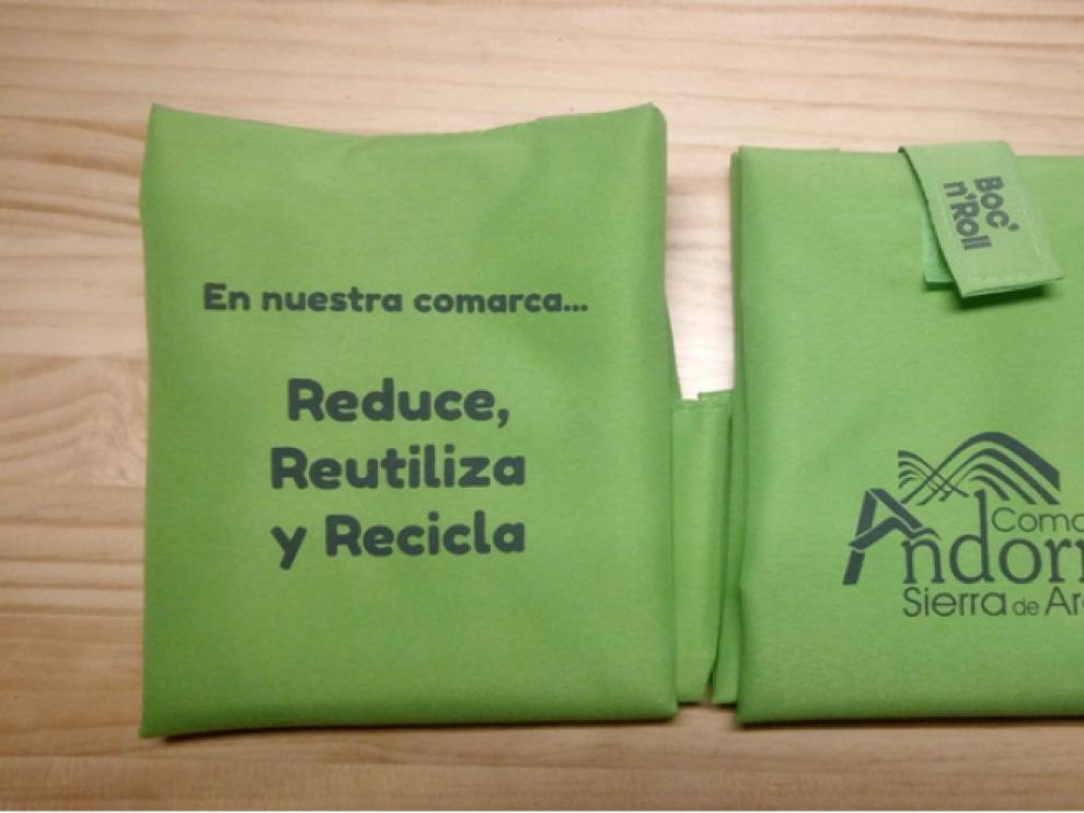 El portabocadillos es verde y lleva el logo de la comarca y un eslogan.