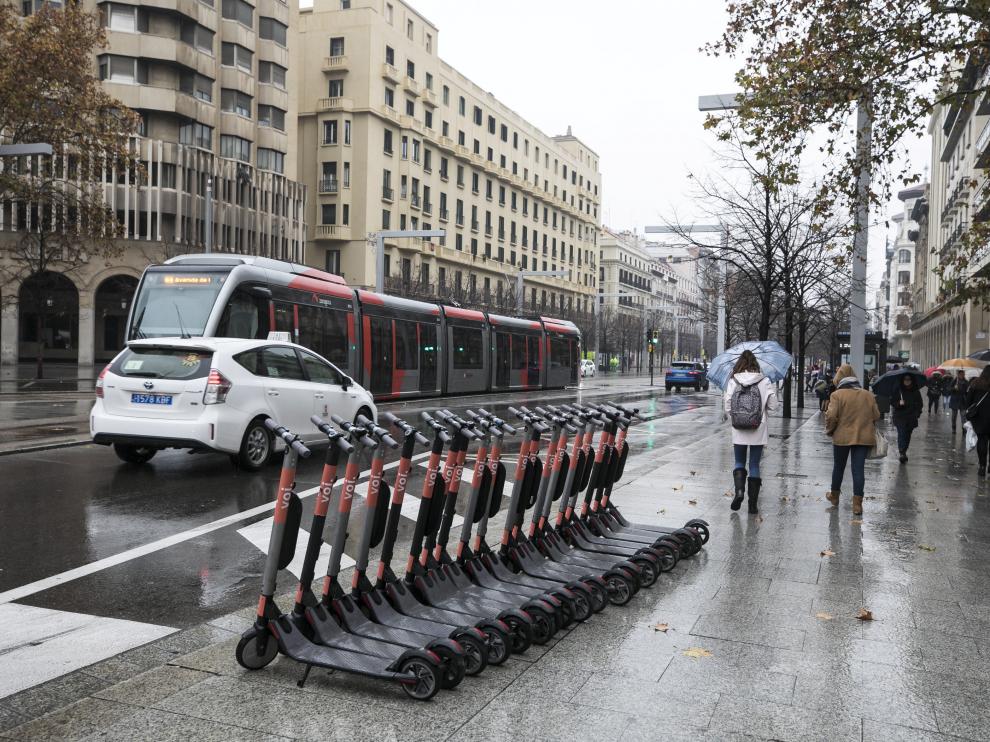Un grupo de patinetes aparcados sobre la acera del paseo de la Independencia.