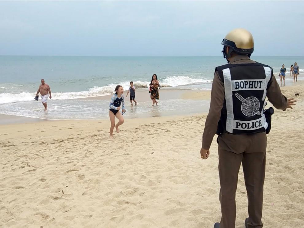 Un policía advierte de la prohibición de baño en la playa de Koh Samui antes de que comenzara la tormenta.
