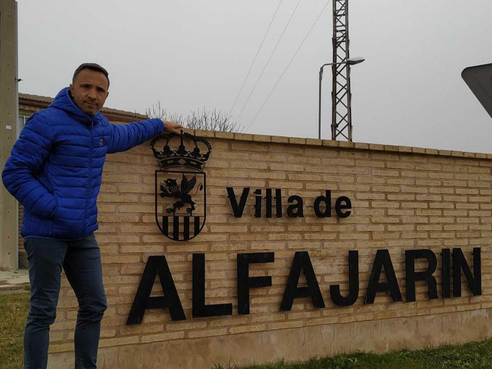 El alcalde de Alfajarín, junto a un letrero con la denominación de la localidad.