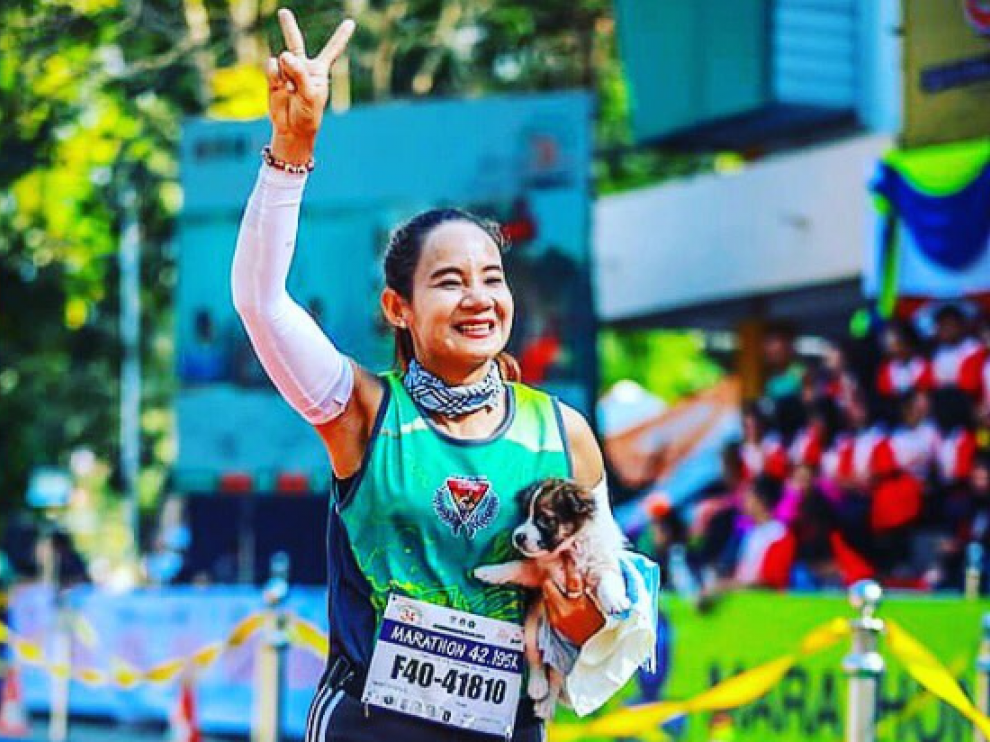 Khemjira Klongsanun con el cachorro en brazos corriendo la carrera en Tailandia.