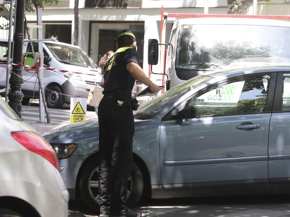 Un policía local de Zaragoza pone una multa a un coche mal aparcado.