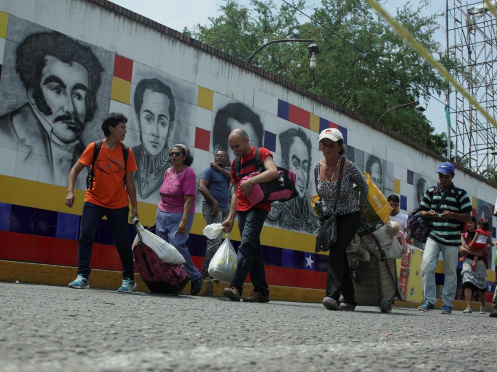 Varias personas cruzan la frontera entre Venezuela y Colombia.