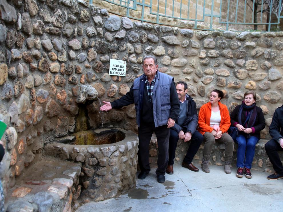 Vecinos de Plasencia del Monte junto a la fuente con el cartel 'Agua no apta para el consumo'