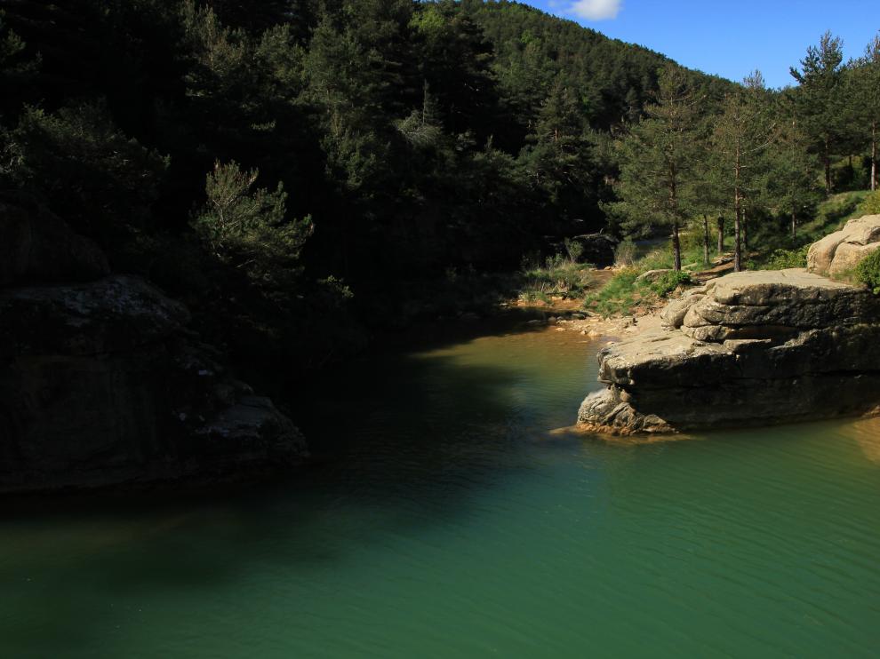 Las aguas verde esmeralda del pozo Pigalo, entre los cantiles de piedra y el bosque que lo rodean.