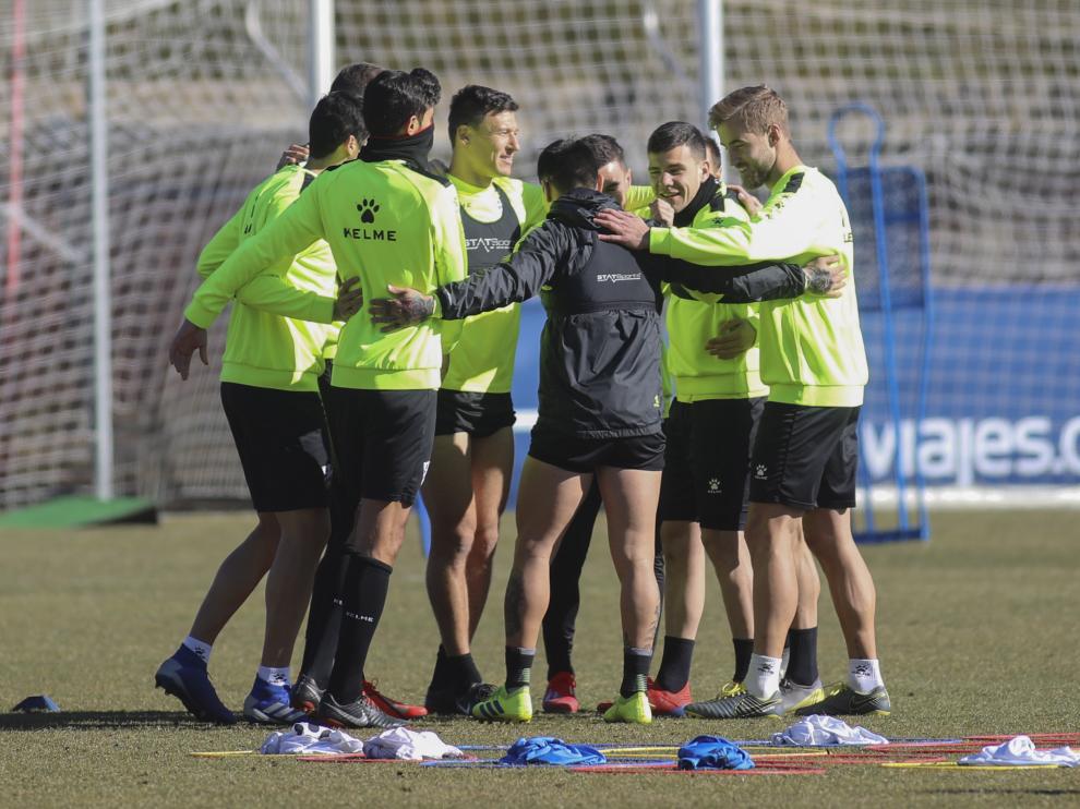 Los jugadores de la SD Huesca realizan un corro en el césped del IES Pirámide.