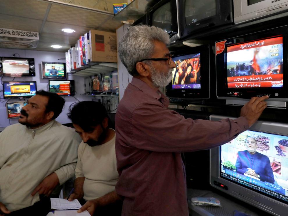 Un hombre mira la televisión que informa del derribo de los cazas indios.