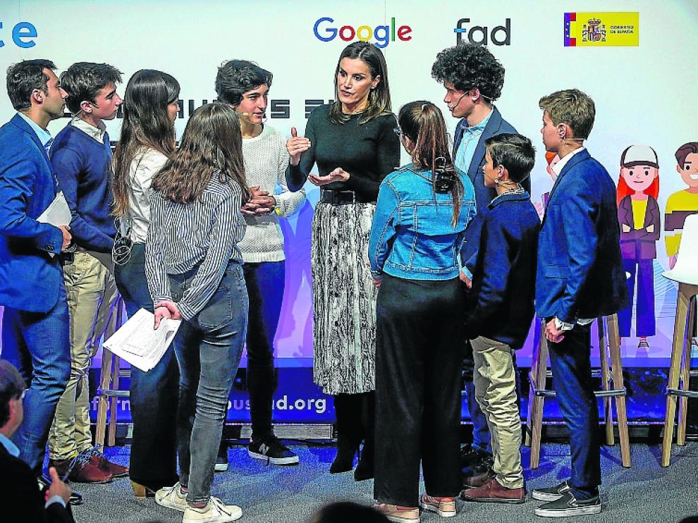 La Reina conversa con varios jóvenes asistentes al acto.