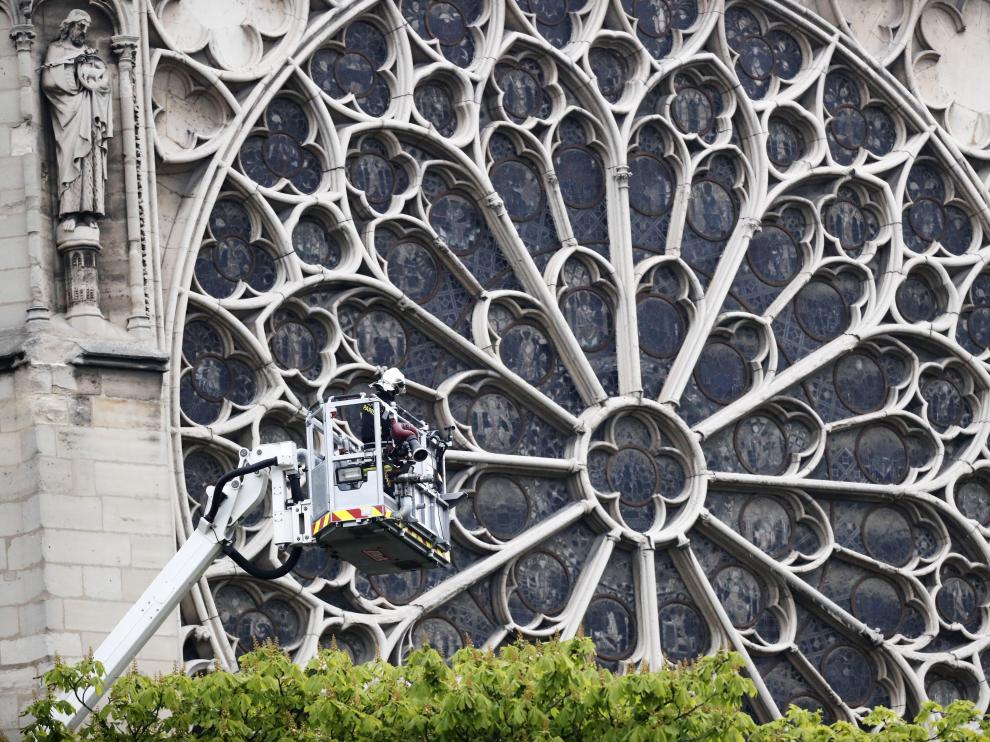 Un bombero trabaja en un elevador junto al rosetón de la catedral de Notre Dame para evaluar los daños.
