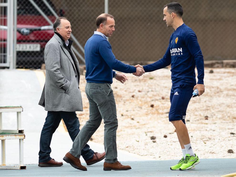 Cristian Lapetra, el presidente del Real Zaragoza, saluda a Miguel Linares en la mañana de este Jueves Santo en la Ciudad Deportiva, acompañado por el responsable de Comunicación del club, Miguel Gay.