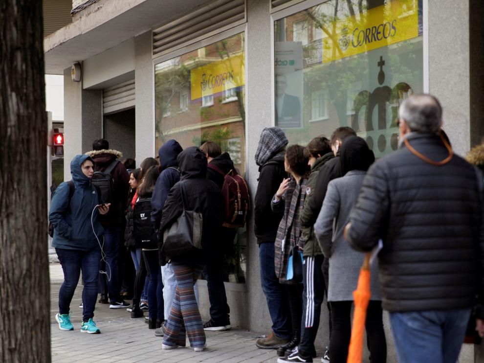 Largas colas de ciudadanos para ejercer el derecho al voto por correo en Madrid.