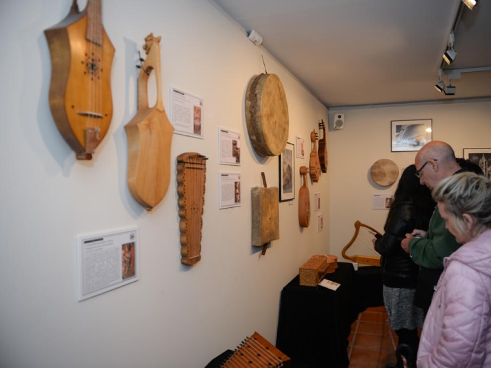 Unos visitantes observan los instrumentos musicales, piezas modernas de modelos antiguos, de la exposicion temporal en el Museo de Albarracín.