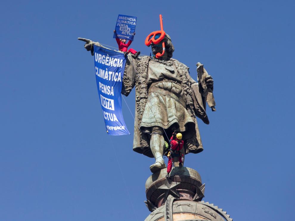 Dos activistas de Greenpeace colocan gafas de buzo a la estatua de Colón para protestar contra el cambio climático.