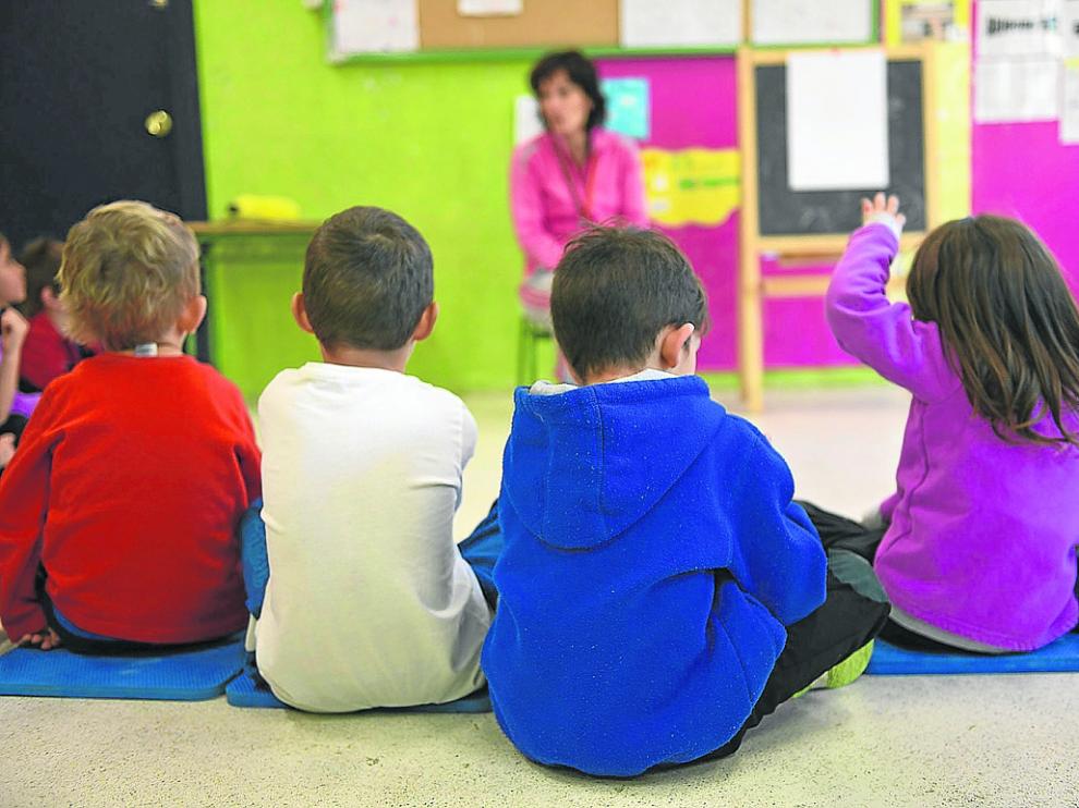 Niños pequeños atienden las explicaciones de la maestra en un colegio de Zaragoza.