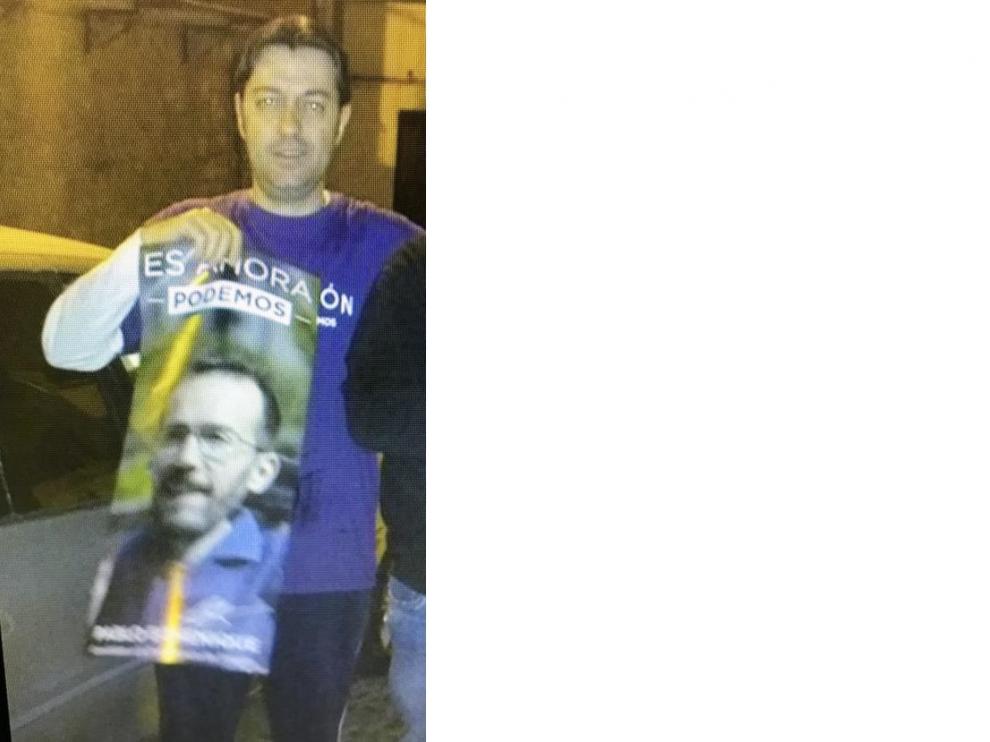 El candidato de Vox en Tarazona, Javier Moya, pegando un cartel electoral de Podemos
