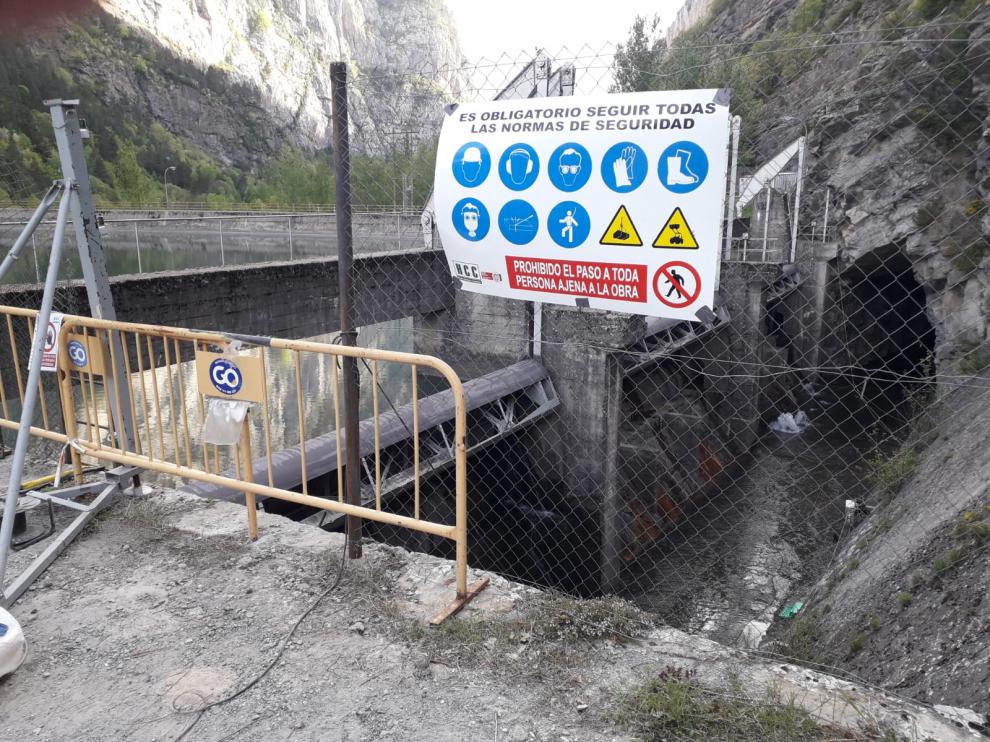 Cartel de obras colocado en la valla que protege el acceso a la presa de Plandescún.