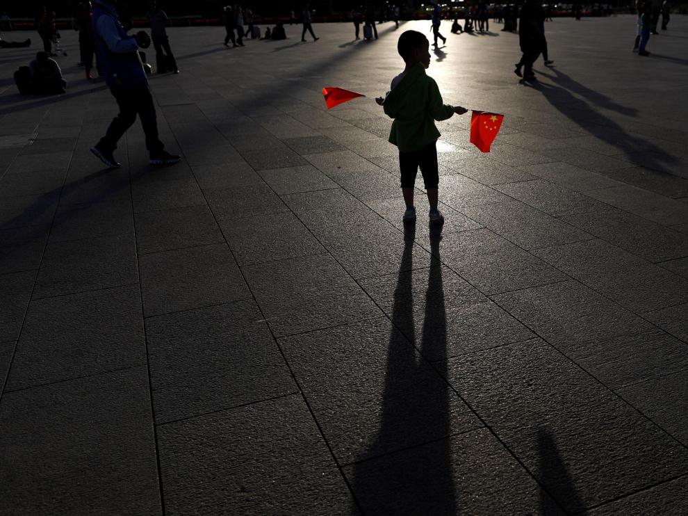 Un niño sostiene dos banderas en la plaza de Tiananmen en Pekín, China.