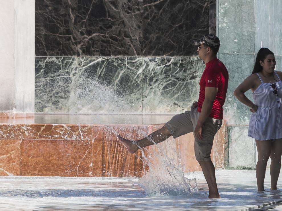 Una pareja se refrescaba este domingo en la fuente de Goya, ubicada en la plaza del Pilar de Zaragoza.