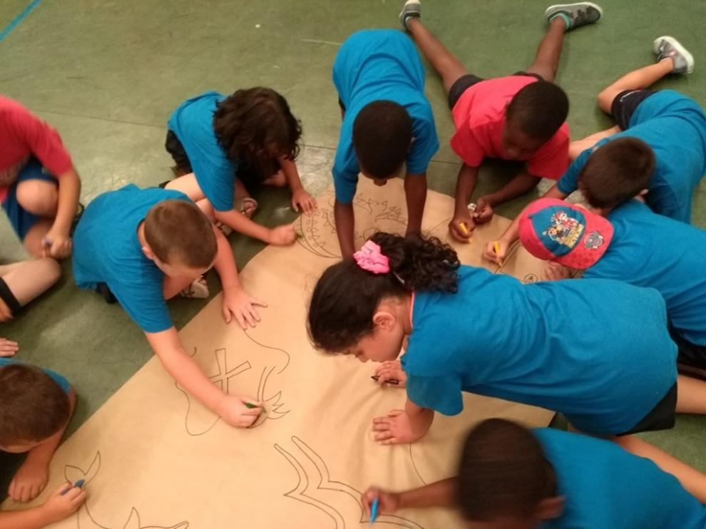 Algunos niños hacen un mural en las colonias urbanas de Cruz Roja