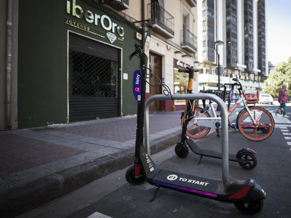 Una bicicleta de Mobike y patinetes, en uno de los aparcamientos habilitados por el Ayuntamiento de Zaragoza.
