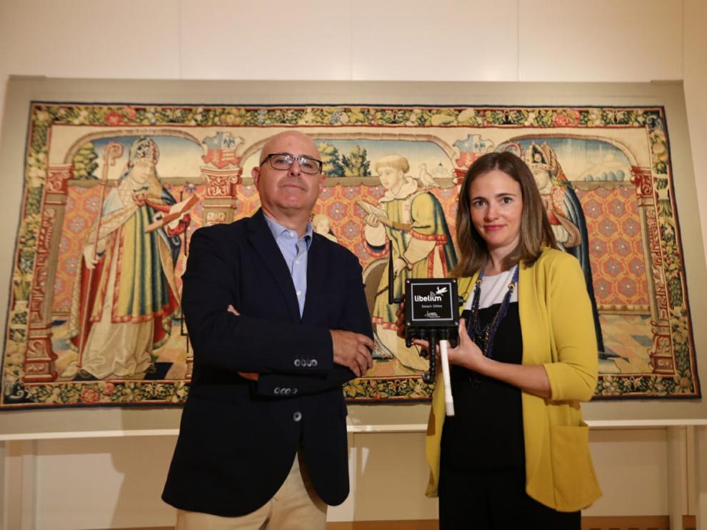Fernando Sarriá y Alicia Asín muestran el sensor delante del tapiz de Roda de Isábena.