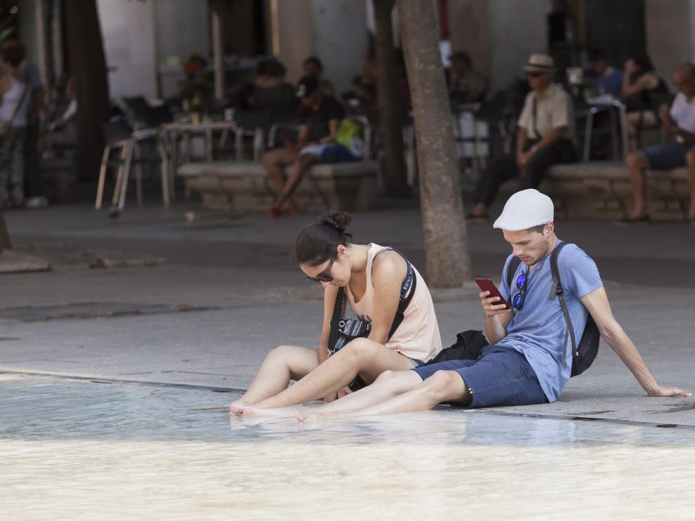Dos personas se refrescan, ayer en la fuente de Goya de la plaza del Pilar de la capital