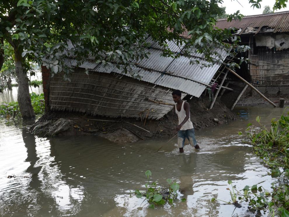 Un hombre camina cerca de su casa, afectada por las inundaciones, en la región de Assam (India).